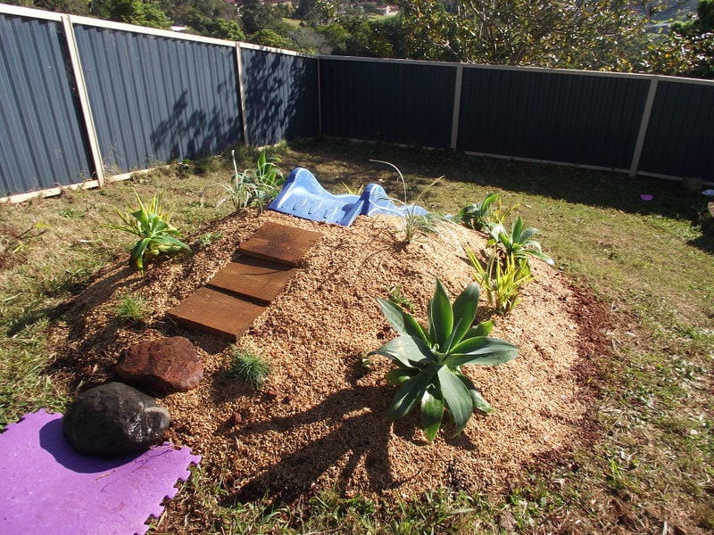 Hill Slide Fun from The Empowered Educator! Add a climbing challenge to your outdoor play area with this simple DIY mound or hill slide. No hardware required and easy to remove when no longer needed! Perfect project for parents, educators and early childhood teachers who value engaging outdoor play spaces! #outdoorplay #diy #outdoorspace #backyard #naturalplay #hillslidefun