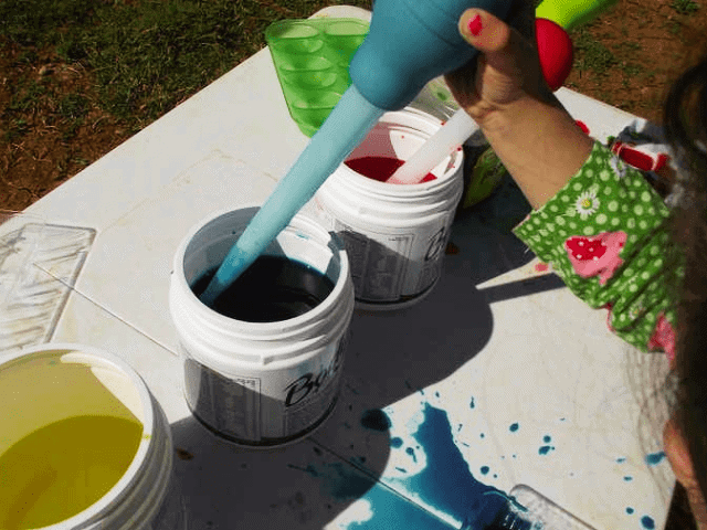 child using a turkey baster and water paint to make a painting