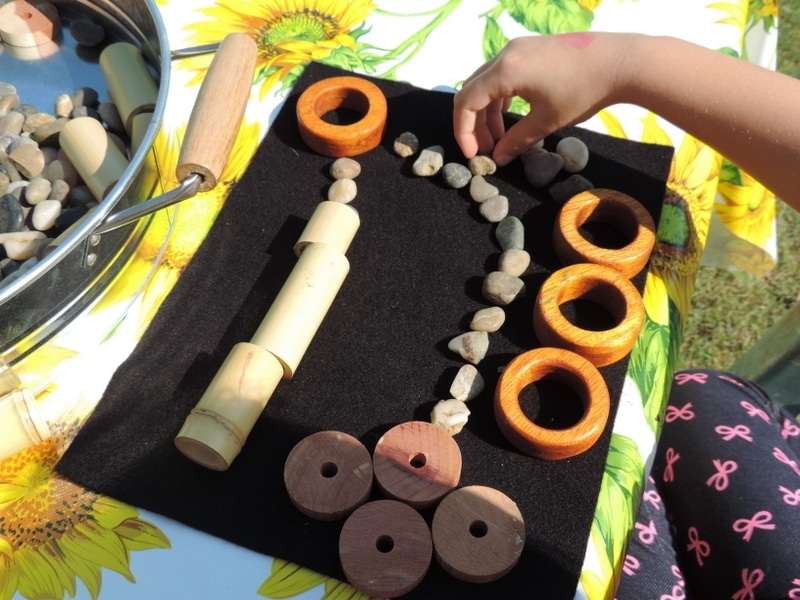 child creating transient artwork with loose parts and natural materials on felt