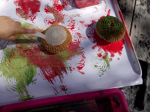 children using dish scrubbers to paint with outside on white paper