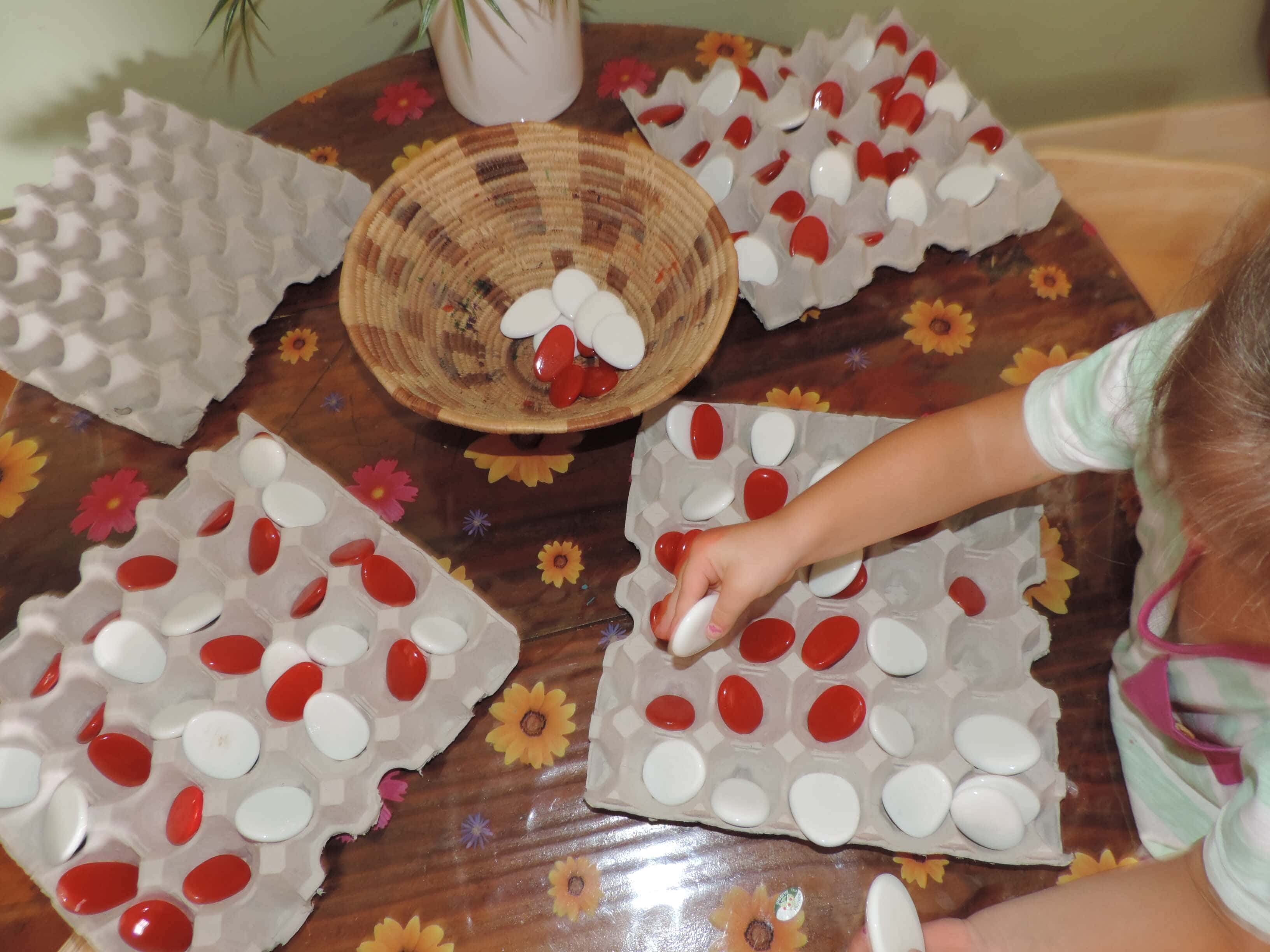 child arranging colured stones into patterns